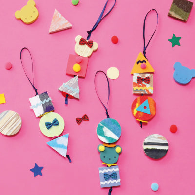 Colorful handmade charms on a pink background with decorative shapes.