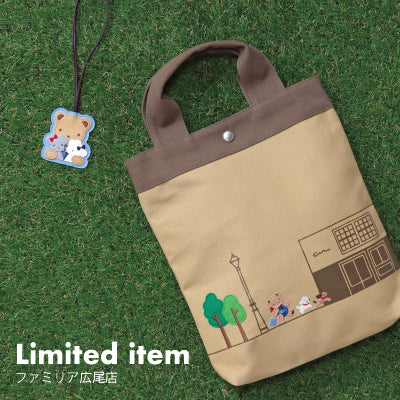 A tan tote bag with illustrations and a keychain, labeled 